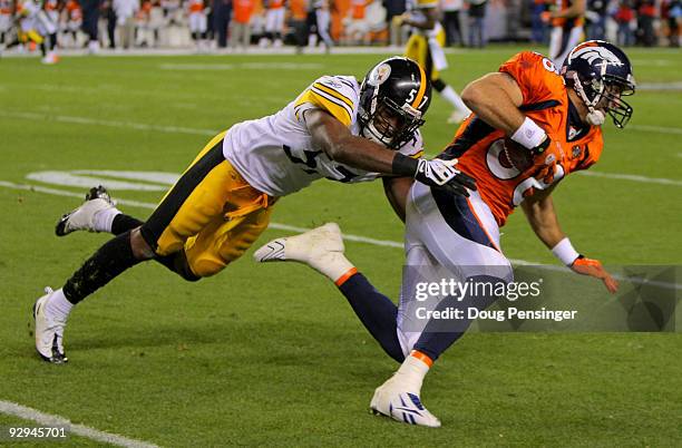 Tony Scheffler of the Denver Broncos makes a reception and is tackled by Keyaron Fox of the Pittsburgh Steelers during NFL action at Invesco Field at...