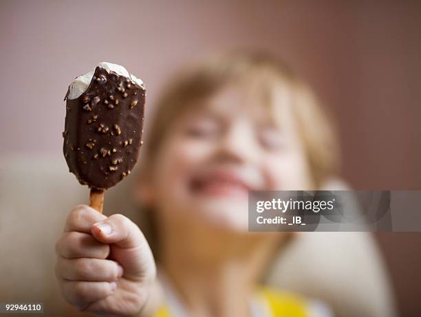 young boy enjoying a chocolate covered ice cream bar - kid eating ice cream stockfoto's en -beelden