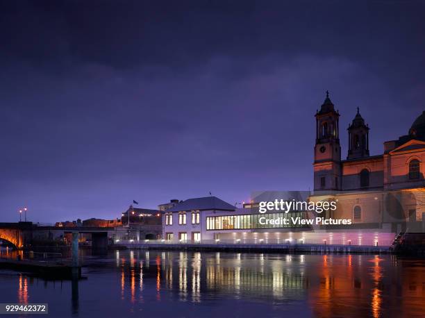 View of exterior across River Shannon at dusk with Athlone Castle in background. Luan Gallery, Athlone, Ireland. Architect: Keith Williams...