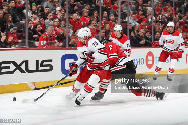 Elias Lindholm of the Carolina Hurricanes and Brent Seabrook of the Chicago Blackhawks battle for the puck in the first period at the United Center...