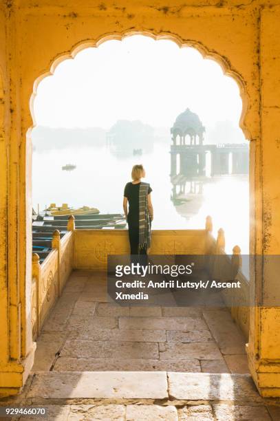 young woman looks out at gadi sagar lake in morning light - jaisalmer stock pictures, royalty-free photos & images