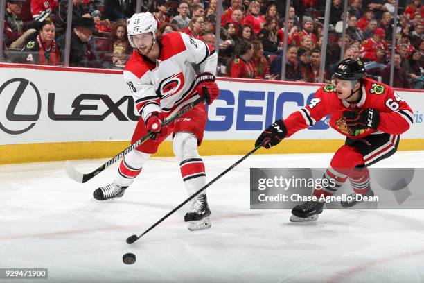 Elias Lindholm of the Carolina Hurricanes hits the puck past David Kampf of the Chicago Blackhawks in the third period at the United Center on March...