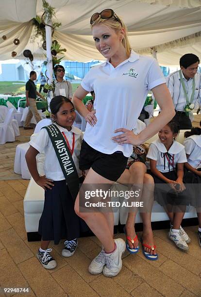 Miss Earth candidate Melinda Heffernan of Australia strikes a pose with Jhenalyn De Guzman, an elementary student after a tree planting activity at...