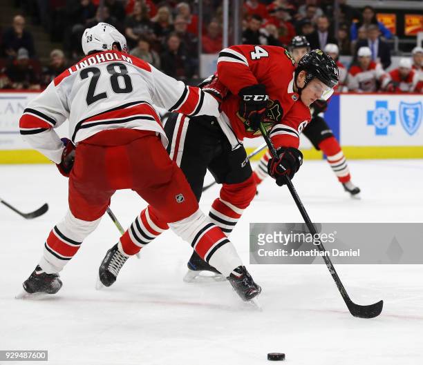 Elias Lindholm of the Carolina Hurricanes hits David Kampf of the Chicago Blackhawks at the United Center on March 8, 2018 in Chicago, Illinois. The...