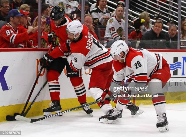 Anthony Duclair of the Chicago Blackhawks is pressure by Klas Dahlbeck and Elias Lindholm of the Carolina Hurricanes at the United Center on March 8,...