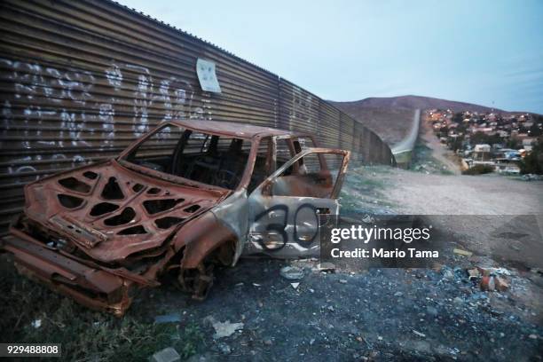 The remnants of a car sit on the Mexico side of the current US/Mexico border wall near to where President Donald Trump's border wall prototypes are...