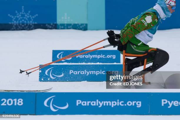 An athlete skis past signs at the nordic skiing venue of the Pyeongchang Paralympic games, in Pyeongchang on March 9, 2018. / AFP PHOTO / Ed JONES