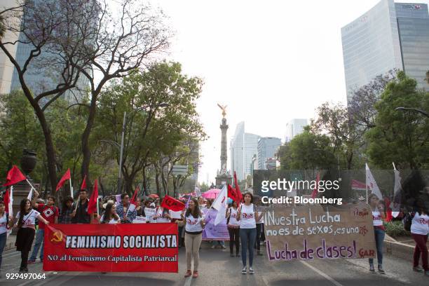 Demonstrators hold signs, flags and banners march in front of the Angel of Independence monument during a national strike on International Women's...