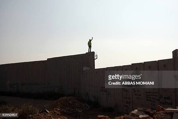 Palestinian activist stands on top of Israel's controversial separation barrier during a protest in the Qalandia refugee camp, near the West Bank...