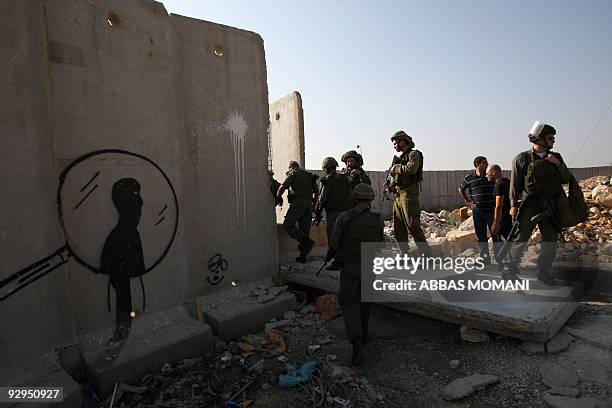 Israeli soldiers inspect a concrete block, part of Israel's controversial separation barrier, after Palestinian and foreign activists pulled it down...