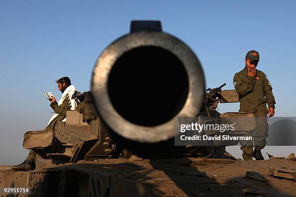 An Israeli soldier recites his morning prayers on his tank as troops stand-down after a night-long training exercise November 10, 2009 near the...