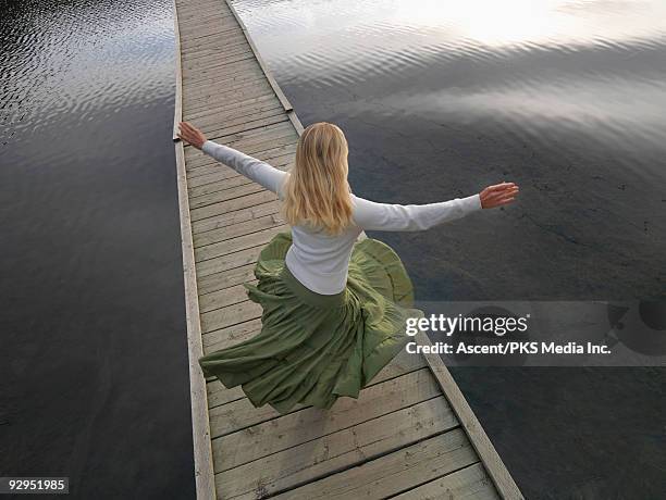 overhead view as woman spins on boardwalk bridge - falda fotografías e imágenes de stock