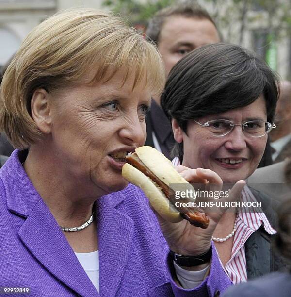 German Chancellor Angela Merkel eats a sausage next to Thuringia Social Minister Christine Lieberknecht during a vist to in the eastern German city...