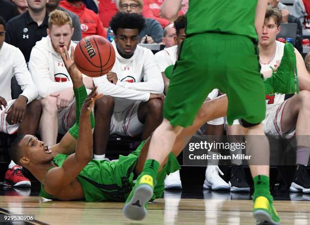 Kenny Wooten of the Oregon Ducks passes to a teammate after diving on the floor in front of the Utah Utes bench to save the ball from going out of...