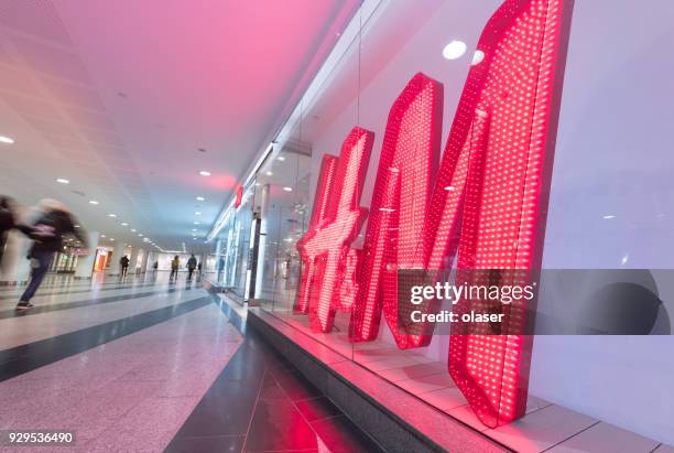 hm h and h h&m sign and motion blurred shopper - nome de marca imagens e fotografias de stock