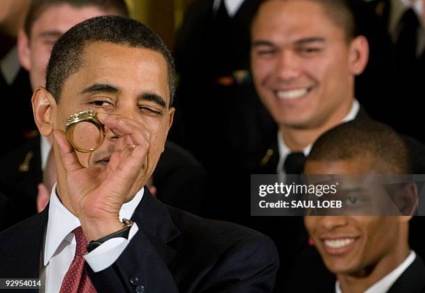 President Barack Obama takes a closer look at a replica championship ring given to him by the US Naval Academy football team as he presents the team...