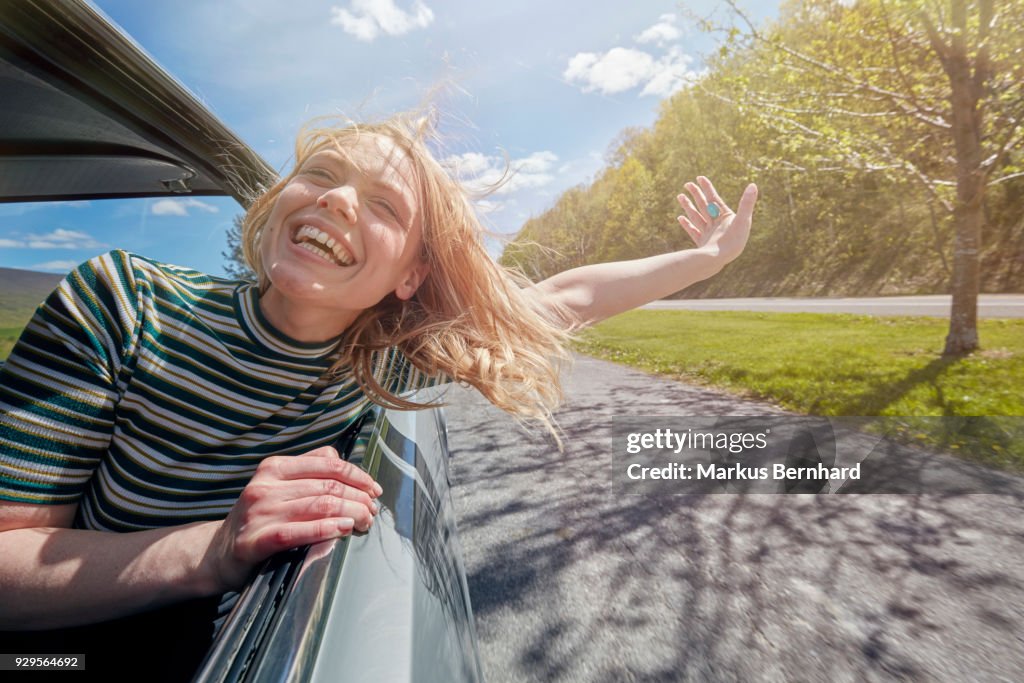Woman sticking head out of window while driving