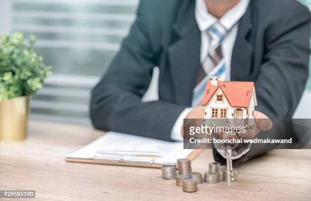 business man hand key and house model - key ring isolated stockfoto's en -beelden