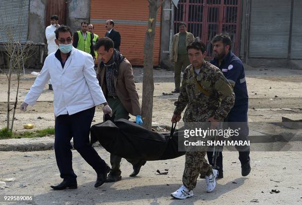 Afghan investigators carry the dead body of suicide attacker who blew himself up in a Shiite area of Kabul on March 9, 2018. - A suicide bomber on...