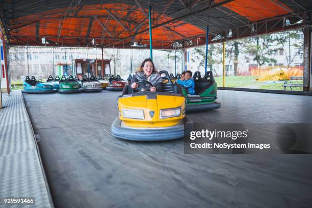 mixed race-familie, bruder, schwester und kaukasischen mutter, treibende autoscooter im vergnügungspark - autoscooter stock-fotos und bilder