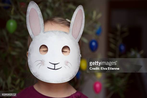 child with eyes closed tight and wearing a rabbit mask - easter mask stock-fotos und bilder