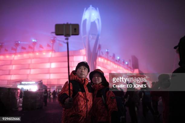 People take photographs in front of the Olympic cauldron before the opening ceremony of the Pyeongchang 2018 Winter Paralympic Games at the...