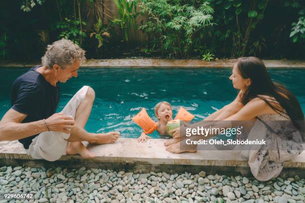 mother and father watching daughter  swimming in swimming pool - expatriate stock pictures, royalty-free photos & images
