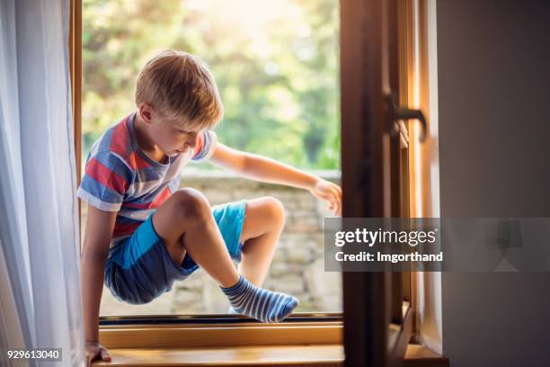 petit garçon entrant dans la maison par une fenêtre - entrer photos et images de collection