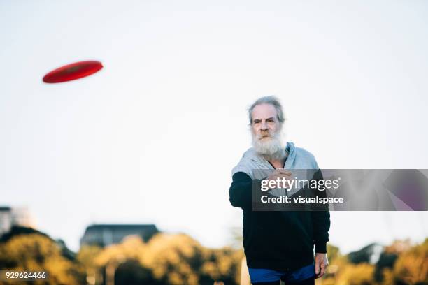 active senior man throwing frisbee - throwing frisbee stock pictures, royalty-free photos & images