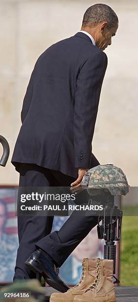 President Barack Obama walks to the stage past one of the 13 pairs of boots, a rifle, and a helmet, memorials during the Fallen Soldier Memorial at...
