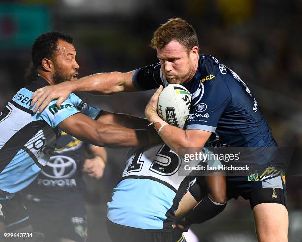 Gavin Cooper of the Cowboys is tackled by James Segeyaro of the Sharks during the round one NRL match between the North Queensland Cowboys and the...