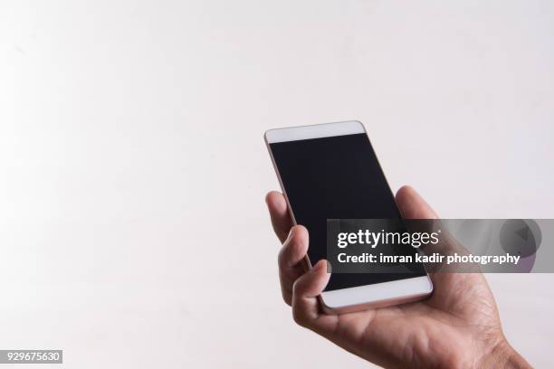 holding a black screen smartphone in white background. - black hand holding phone stock-fotos und bilder
