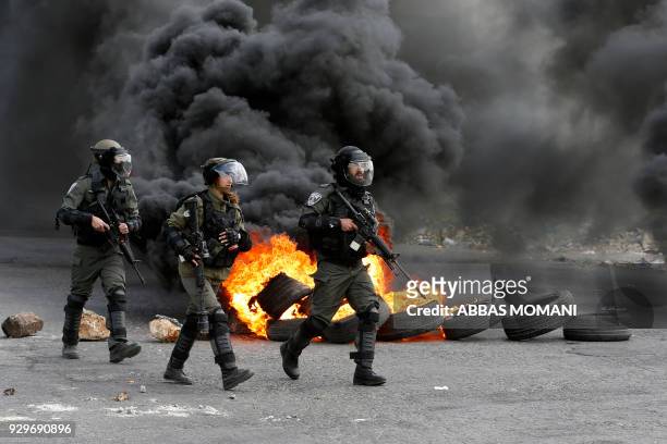 Israeli border guards advance down a street during clashes with Palestinian protesters following a demonstration in the West Bank city of Ramallah on...