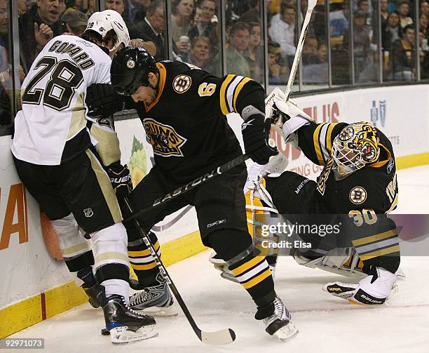 Tim Thomas of the Boston Bruins falls over as teammate Dennis Wideman and Eric Godard of the Pittsburgh Penguins fight for the puck on November 10,...