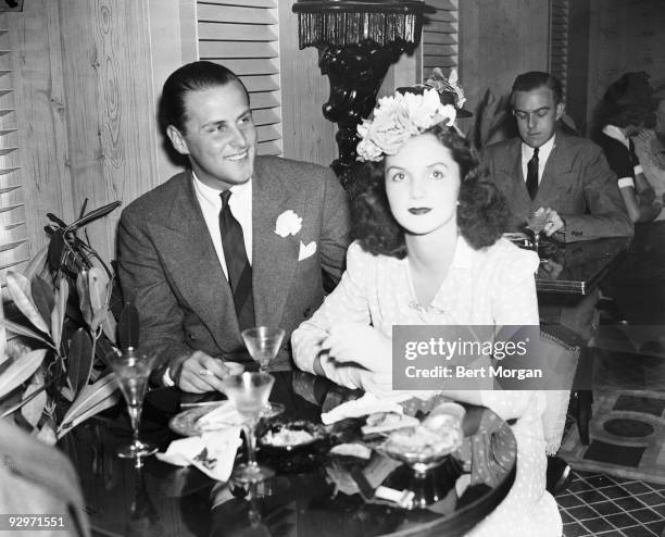 Billy Livingston and Brenda Frazier sitting at a table with cocktails, c 1935