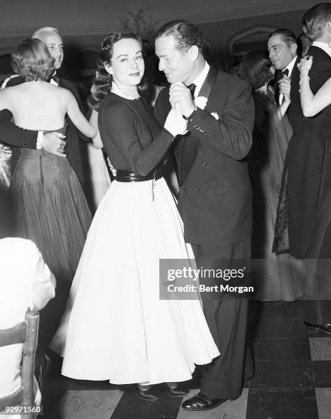 Paulette Goddard dances with Jose Dorelis who is wearing a monocle on a crowded dance floor at Belmont Park Race track, New York, c1949