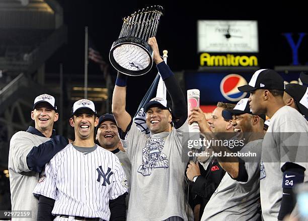 Derek Jeter of the New York Yankees holds up the trophy as he celebrates with A.J. Burnett , Jorge Posada , Mariano Rivera and Robinson Cano after...