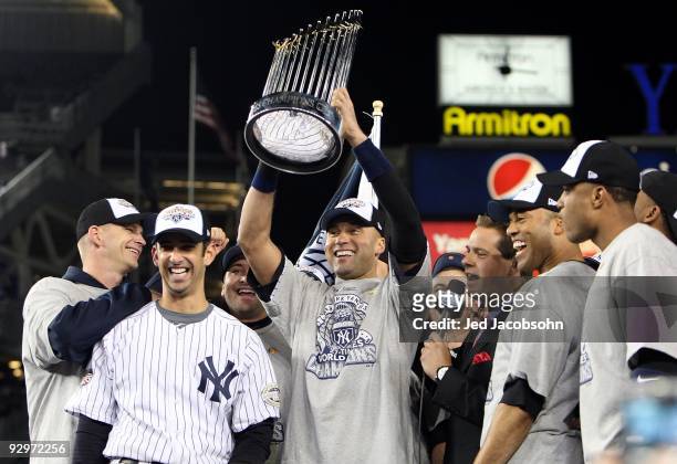 Derek Jeter of the New York Yankees holds up the trophy as he celebrates with A.J. Burnett , Jorge Posada , Mariano Rivera and Robinson Cano after...
