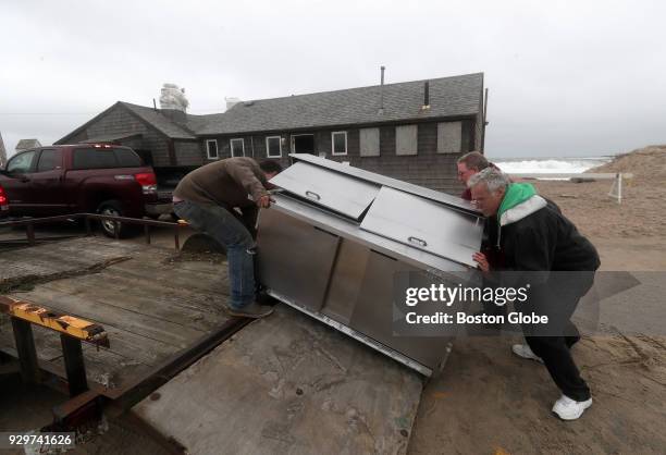 John Ohman, owner of Liam's on Nauset Beach in Orleans, MA, at far right in green hoodie, removes equipment from the seafood shack with the help of...