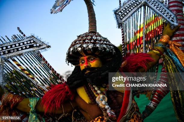 An Indian artist performs traditional folk dance dressed as demon-king Ravana during a cultural event in New Delhi on March 9, 2018. / AFP PHOTO /...