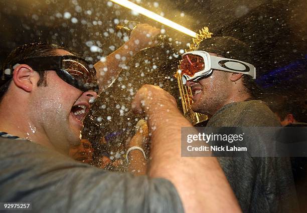 Phil Hughes and Joba Chamberlain of the New York Yankees celebrate with champagne and the trophy in the locker room after their 7-3 win against the...