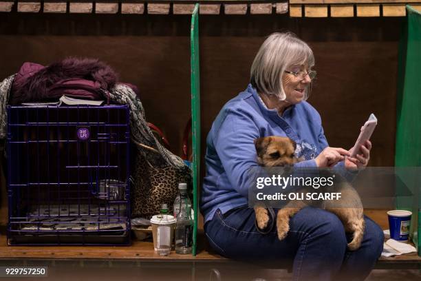 Woman sits with her Border Terrier dog on the second day of the Crufts dog show at the National Exhibition Centre in Birmingham, central England, on...