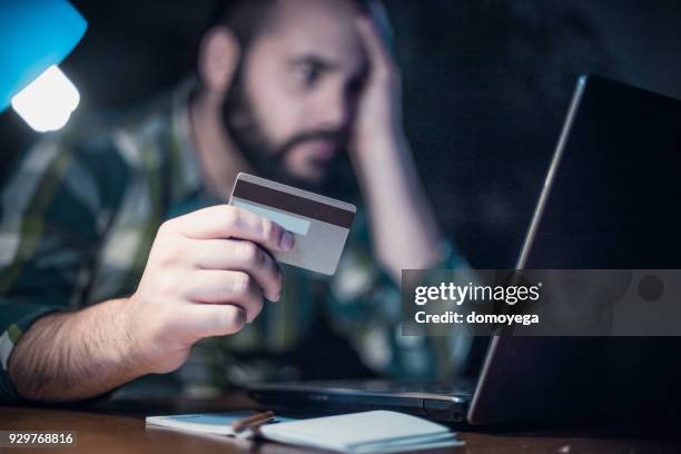 close-up of a man paying bills from home by using a laptop and a credit card - credit score stock pictures, royalty-free photos & images