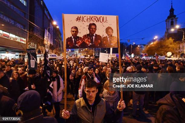 Protesters holds placards showing Slovakia's Prime Minister Robert Foco and Interior Minister Robert Kalinak with blood on their hands during a rally...