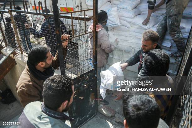 Picture taken on March 9, 2018 shows humanitarian aid being distributed in the Syrian town of Douma in the rebel-held enclave of Eastern Ghouta on...