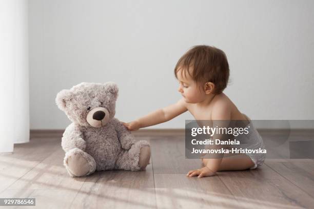 baby girl playing on the floor with teddy bear - teddybear imagens e fotografias de stock