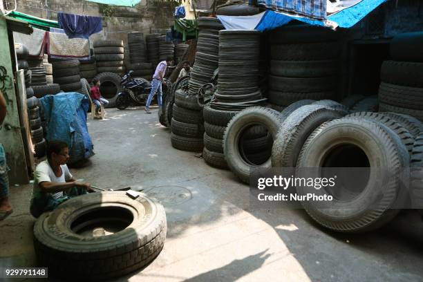 The Used Tyre repair a Narrow Side Street in Kolkata city before they are sold in a second-hand Motors Parts Market ,ALL SIZES Brand: GOODYEAR, CEAT,...