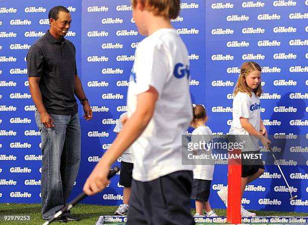 Golfer Tiger Woods helps young children with their golf at a promotional event before the Australian Masters tournament -- Woods' first tournament in...
