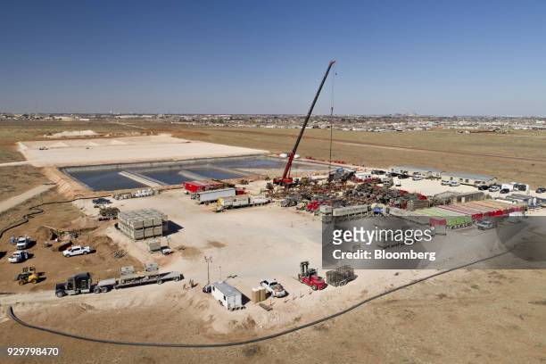 Crane secures a wireline, a cable used to lower and raise tools and other equipment in a well shaft, above one of six Chevron Corp. Oil wells being...