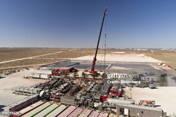 Crane secures a wireline, a cable used to lower and raise tools and other equipment in a well shaft, above one of six Chevron Corp. Oil wells being...